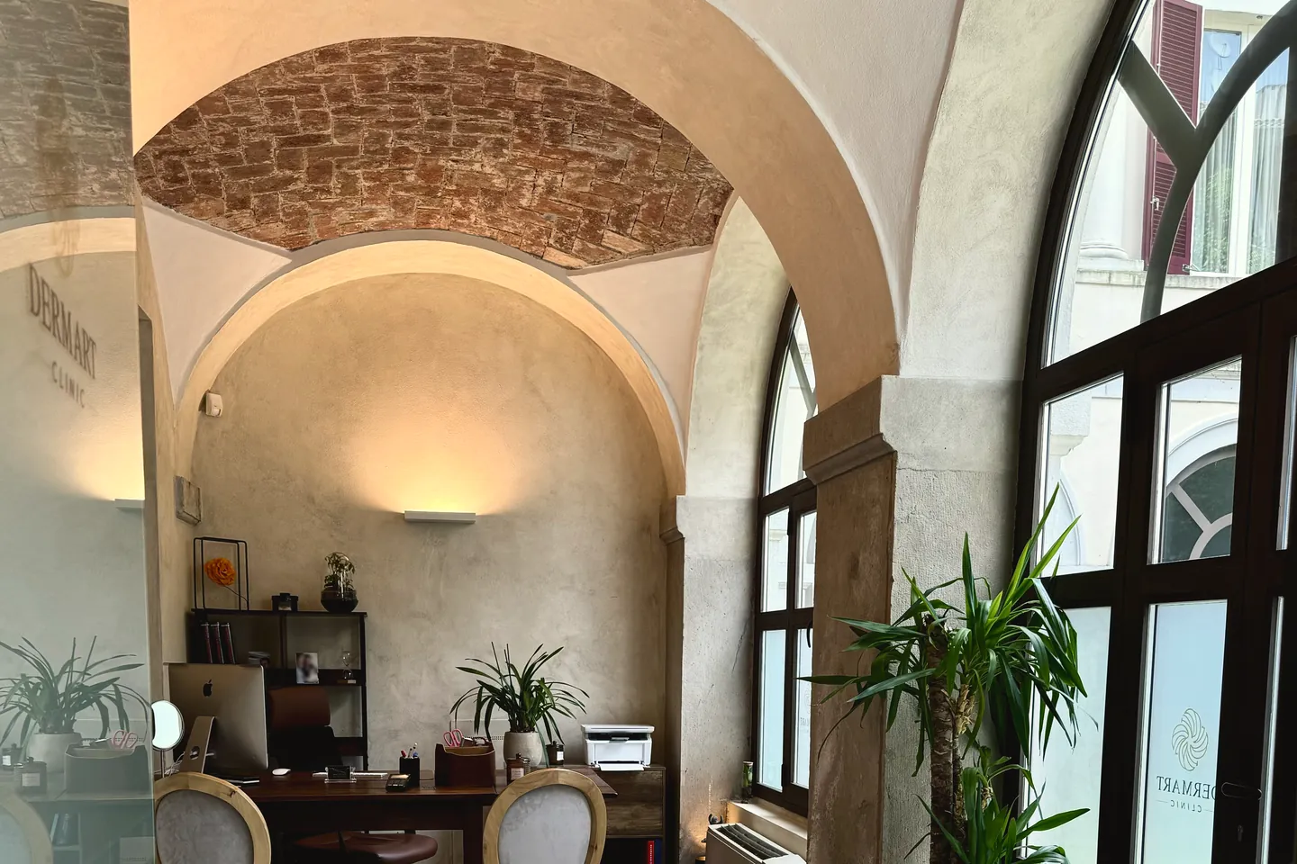 Lo studio di Derm Art Clinic in via Donizetti 4: le volte in mattoni, gli archi e la finestra ad arco sopra la scrivania.