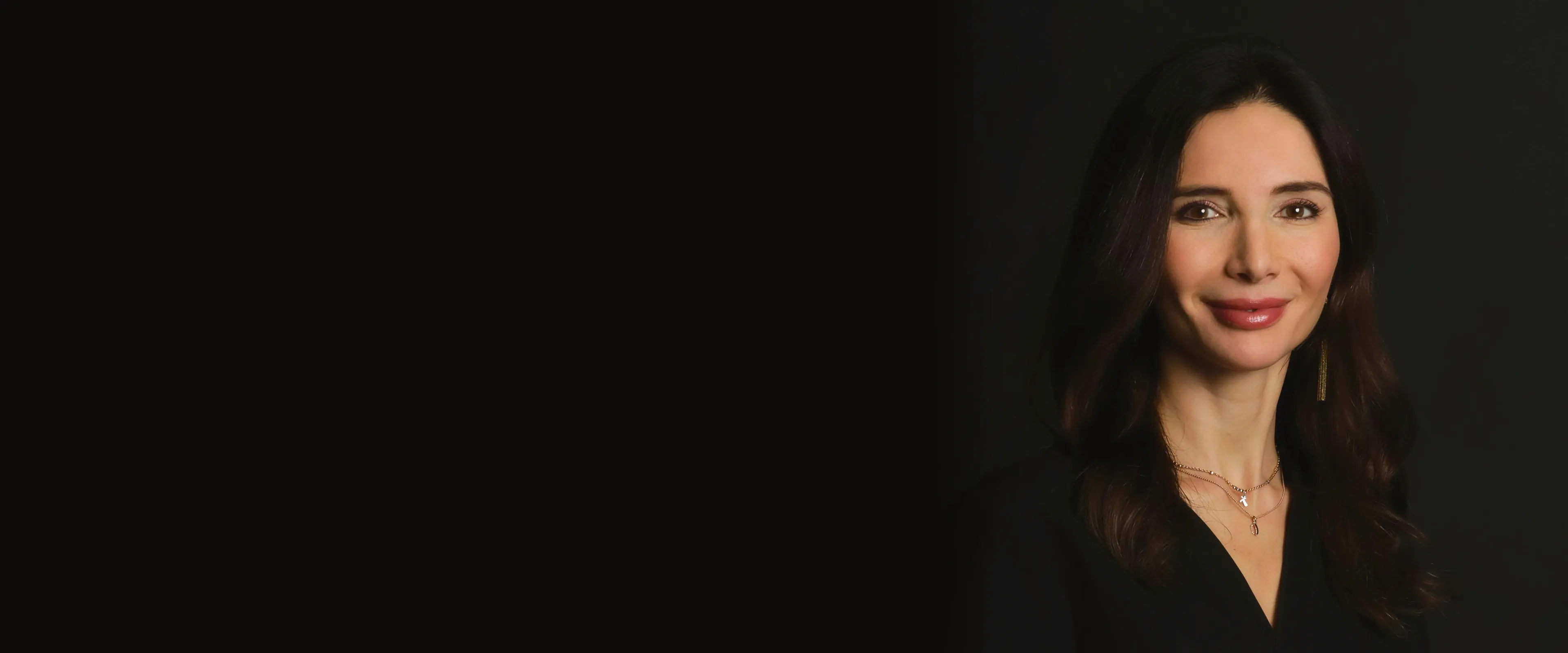 La Dott.ssa Laura Balint su fondo nero, a destra, con un sorriso calmo e una luce calda di lato.